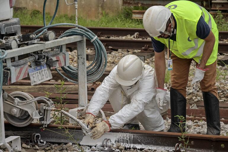 Empleados de ViaMobilidade, una empresa que gestiona las líneas de metro y tren en el área metropolitana de São Paulo, trabajan en la pintura de las vías férreas en Osasco, estado de São Paulo, Brasil.