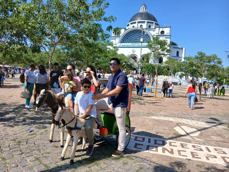 Los niños acompañados de sus padres felices se toman la fotografía sobre el emblemático caballito de Caacupé.