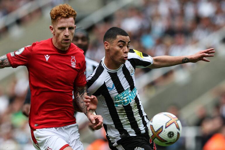 El centrocampista inglés del Nottingham Forest Jack Colback (izq.) lucha por el balón con el centrocampista paraguayo del Newcastle United, Miguel Almirón, durante el partido de fútbol de la Premier League inglesa entre el Newcastle United y el Nottingham Forest en St James' Park en Newcastle-upon-Tyne, noreste de Inglaterra, el 6 de agosto de 2022.