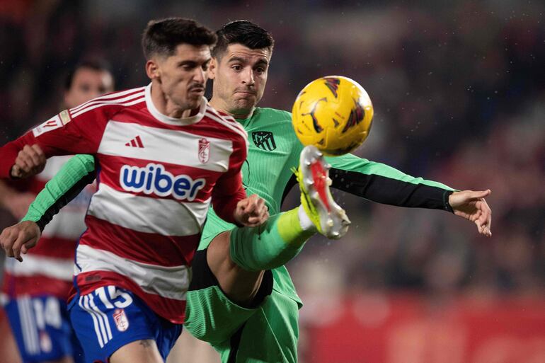 Álvaro Morata puntea el balón anticipándose a Carlos Neva, defensor de Granada, durante el partido que Atlético Madrid ganó ayer 1-0.