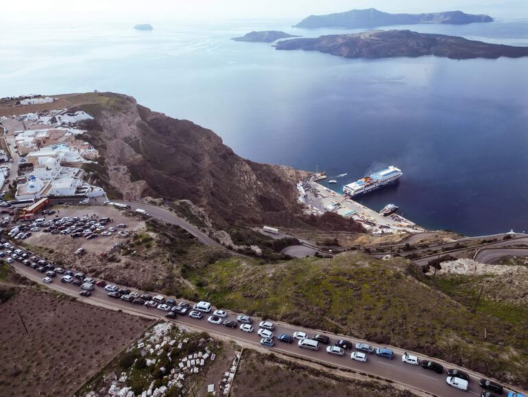 Residentes y visitantes de Santorini formando colas con sus coches hacia el puerto de Athinios, mientras abandonan la isla debido al aumento de la actividad sísmica de los últimos días.