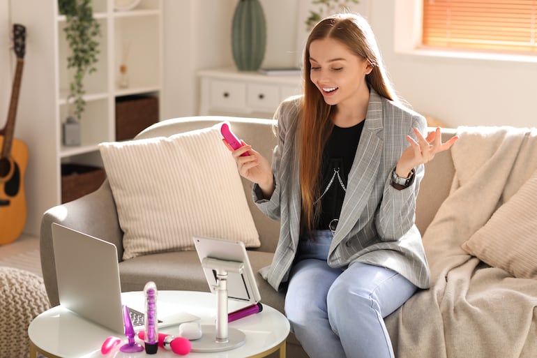 Blogger femenina con vibrador conduciendo educación sexual en línea en casa.