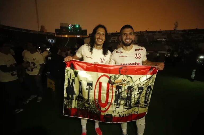 Williams Riveros (i) exhibe una bandera de Universitario con un compañero en el estadio Matute, donde Alianza Lima apagó las luces para que su acérrimo rival no pudiera recibir el trofeo de campeón.