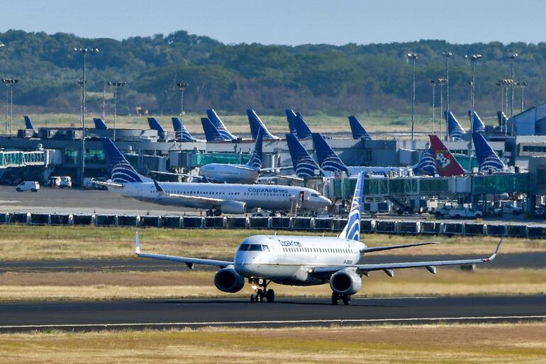 Un avión de Copa Airlines rueda en una pista mientras otros se sientan en la pista del Aeropuerto Internacional de Tocumen.