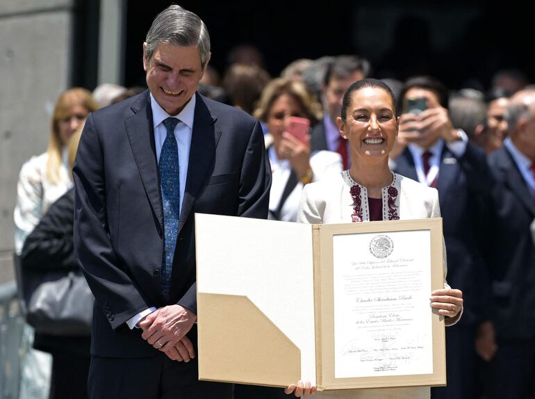 La presidenta electa de México, Claudia Sheinbaum (R), junto a su esposo Jesús María Tarriba, muestra el certificado de su victoria en las pasadas elecciones presidenciales del 2 de junio en el Tribunal Electoral del Poder Judicial de la Federación (TEPJF), en la Ciudad de México el 15 de agosto.