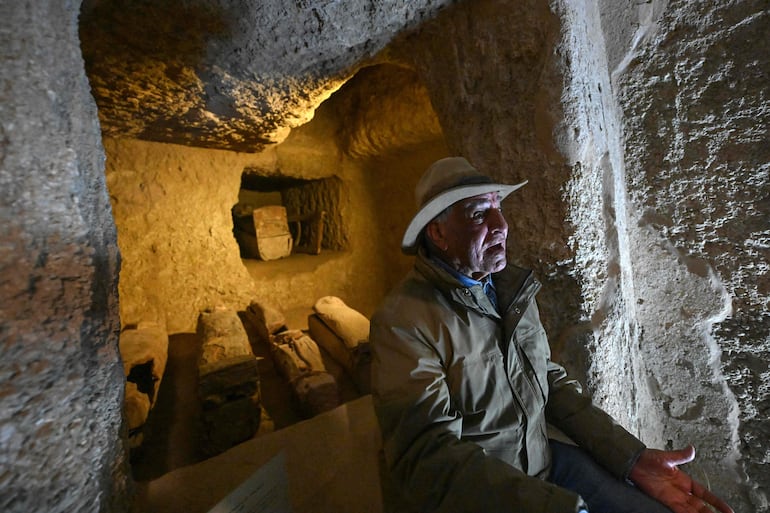 El arqueólogo egipcio Zahi Hawass conversa con periodistas frente a pozos funerarios y ataúdes de madera de la dinastía XVII.