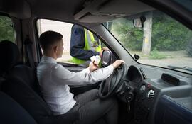 Un conductor entrega sus documentos y billetes a un policía. (Foto ilustrativa).
