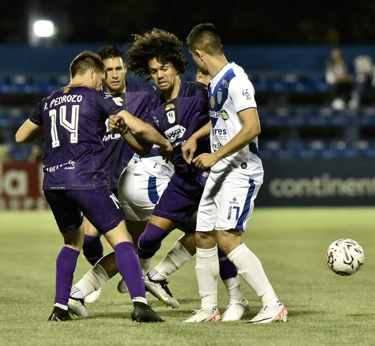 Los jugadores de Tacuary y Ameliano intentan quedarse con el control de la pelota, el cual se les escapa por detrás.