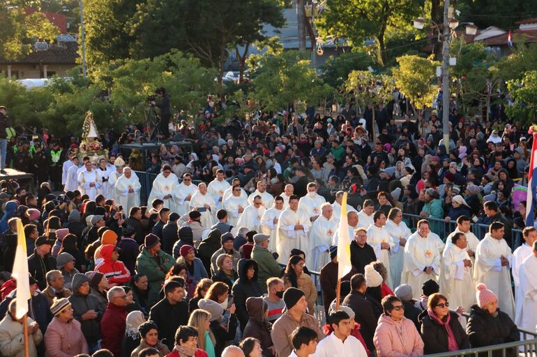 Sacerdotes del Clero de Cordillera, junto a la imagen de la Virgen de los Milagros de Caacupé, caminan hacia el altar en medio de la multitud de fieles reunida en la explanada de la Basílica en la fría mañana del domingo. 