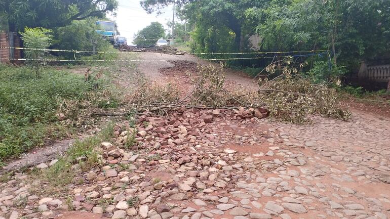 calle con piedras levantadas, ramas. Una cinta clausura el acceso