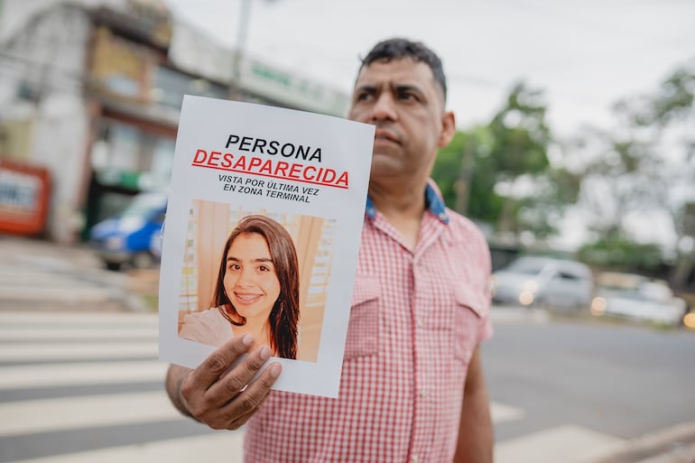 Imagen ilustrativa: un hombre sostiene un afiche sobre la desaparición de una joven.