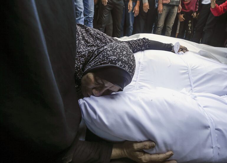 Una mujer llora sobre el cuerpo de uno de los fallecidos en un bombardeo israelí sobre el campo de refugiados de Nuiserat, en Gaza, el domingo.