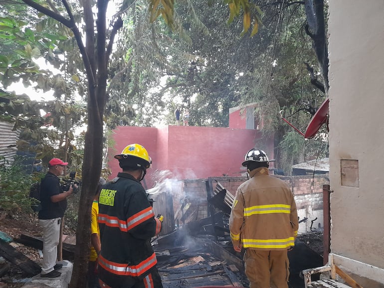 Bomberos observan la vivienda consumida por las llamas en el barrio Ricardo Brugada esta madrugada de lunes.