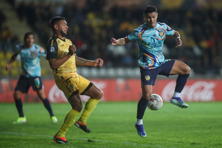 Andrés Chávez (i) de Coquimbo disputa el balón con Rodi Ferreira de Luqueño este jueves en un partido de la fase de grupos de la Copa Sudamericana entre Coquimbo Unido y Sportivo Luqueño en el estadio Municipal Francisco Sánchez en Coquimbo (Chile).