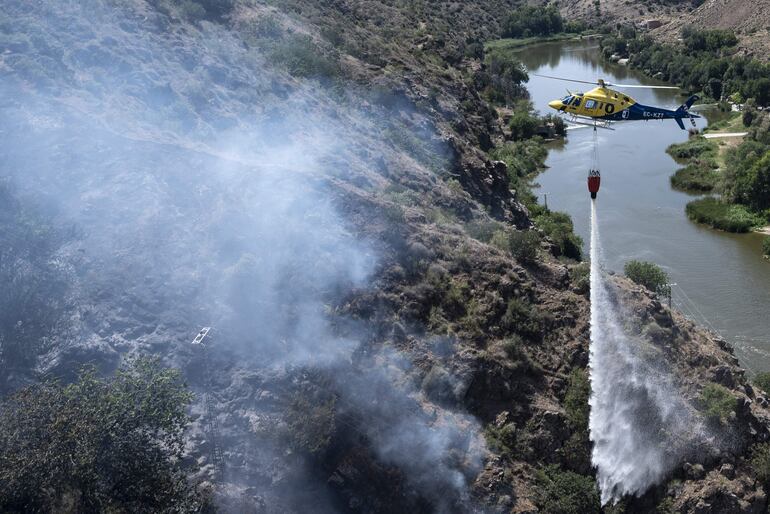 Imagen de archivo y referencia: un helicóptero con bolsa de agua trabaja en la extinción de un incendio que se ha detectado en las inmediaciones de la ermita de la Virgen del Valle de Toledo (Castilla la Mancha).