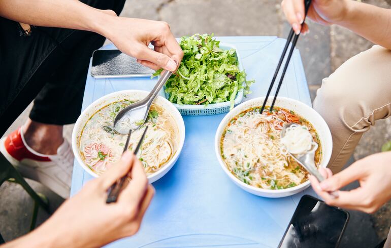 Personas comiendo Pho, plato vietnamita.