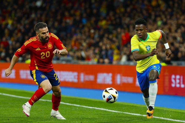 MADRID, 26/03/2024.- El delantero de la selección brasileña Vinicius Jr. (d) se escapa de Dani Carvajal, de la selección española, durante el partido amistoso que las selecciones nacionales de fútbol de España y Brasil disputan hoy martes en el estadio Santiago Bernabéu, en Madrid. EFE/Mariscal
