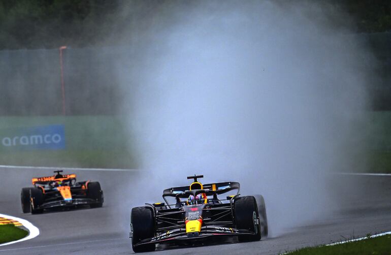 Max Verstappen del Red Bull Racing, maniobra  su RB19 en la lluvia  seguido muy de cerca por Óscar Piastri de Mc Laren.