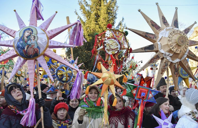 Ucranianos cantan villancicos y llevan estrellas decoradas de Belén durante un desfile en el centro de Lviv, Ucrania occidental, el 30 de diciembre de 2024, como parte de las próximas celebraciones de año Nuevo en medio de la invasión rusa en curso. 