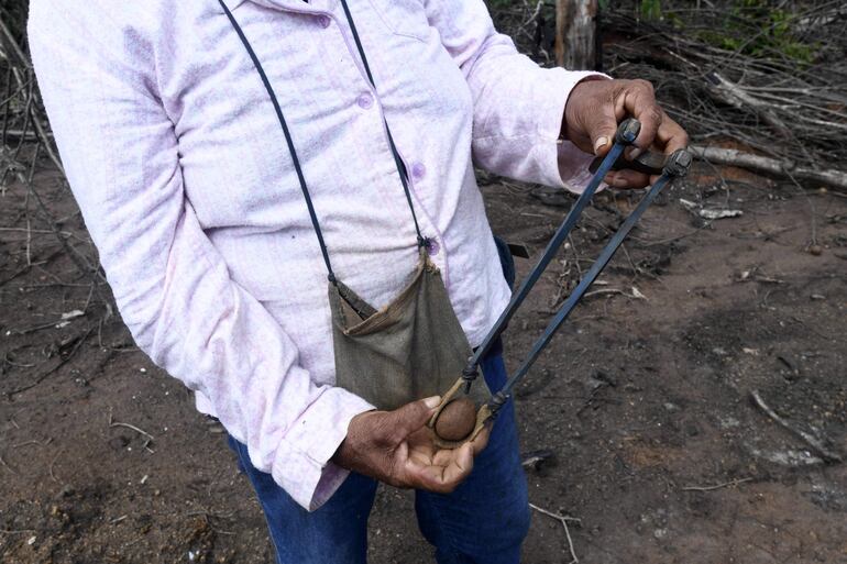 Carmen Peña muestra una resortera con una bomba de semillas utilizada para reforestar áreas afectadas por incendios forestales en Santa Ana de Velasco, en el departamento de Santa Cruz, en la región de la Chiquitanía, Bolivia.