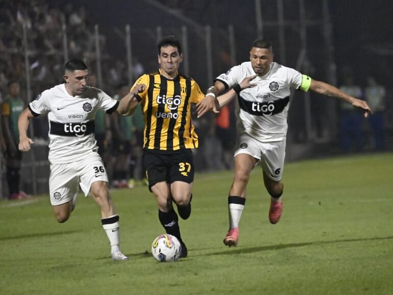 Daniel Pérez (c), jugador de Guaraní, pelea por el balón entre dos futbolistas de Olimpia en el partido por la duodécima fecha del torneo Clausura 2024 del fútbol paraguayo en el estadio Rogelio Silvino Livieres, en Asunción, Paraguay.