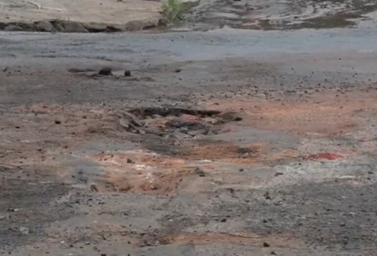 Un enorme bache se ve en la calle Teniente Otazú, en zona del Mercado 4. Además, agua de caño roto riega la capa asfáltica.