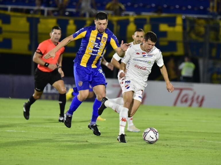 Rodrigo Rojas (i), volante del Sportivo Luqueño, y Mathías Martínez, de Nacional, pelean por el balón en el partido de la primera rueda del torneo Apertura 2023 del fútbol paraguayo en el estadio Defensores del Chaco, en Asunción.