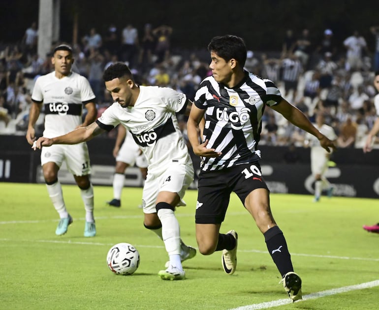 Fernando Cardozo (i), jugador de Olimpia, pelea por el balón con Lorenzo Melgarejo, futbolista de Libertad, en un partido por el torneo Apertura 2024 del fútbol paraguayo en el estadio La Huerta, en Asunción, Paraguay.