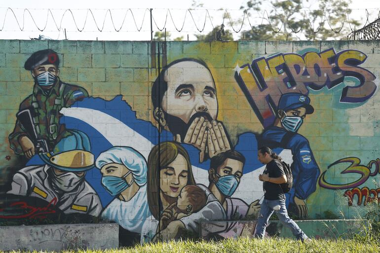 Un hombre camina frente a un mural alusivo al presidente de El Salvador, Nayib Bukele hoy, en San Salvador (El Salvador). 