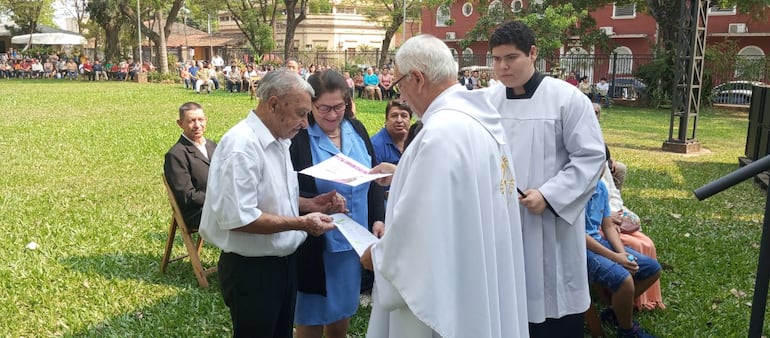 Monseñor Enrique Meyer entregando un reconocimiento a una pareja que que celebro su aniversario Nº50 como marido y mujer.