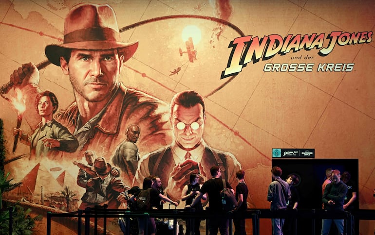 Los visitantes se detienen en el stand del videojuego “Indiana Jones and the Great Circle” durante el día de prensa de la feria de videojuegos Gamescom, en Colonia.