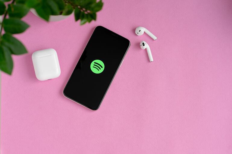 Un teléfono celular conectado a Spotify con dos auriculares