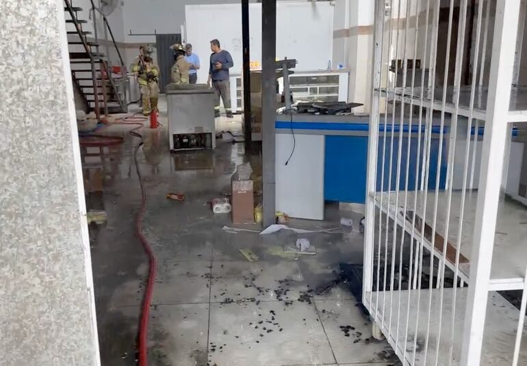 Bomberos voluntarios verificando el interior del local siniestrado.