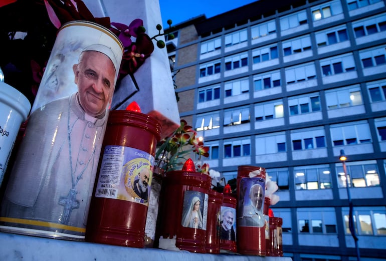 Una vela con la imagen del Papa Francisco, al pie de la estatua de San Juan Pablo II en las afueras del Hospital Universitario Gemelli, en Roma.