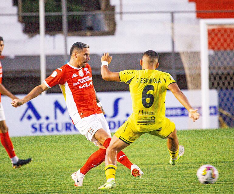 El mediocampista de General Caballero Jorge Mendoza ensaya un pase ante la oposición de José Espínola, de Recoleta Football Club.