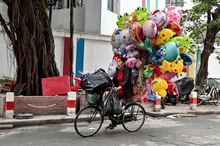 Una vendedora callejera transporta globos en una bicicleta en Hanoi.