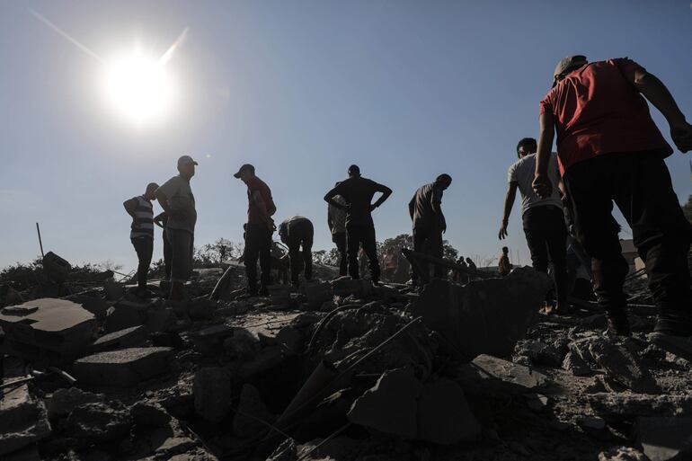 Varias personas buscan entre los escombros de una casa destruida por un bombardeo israelí el jueves en la zona de refugiados de Al Maghazi, en la Franja de Gaza.