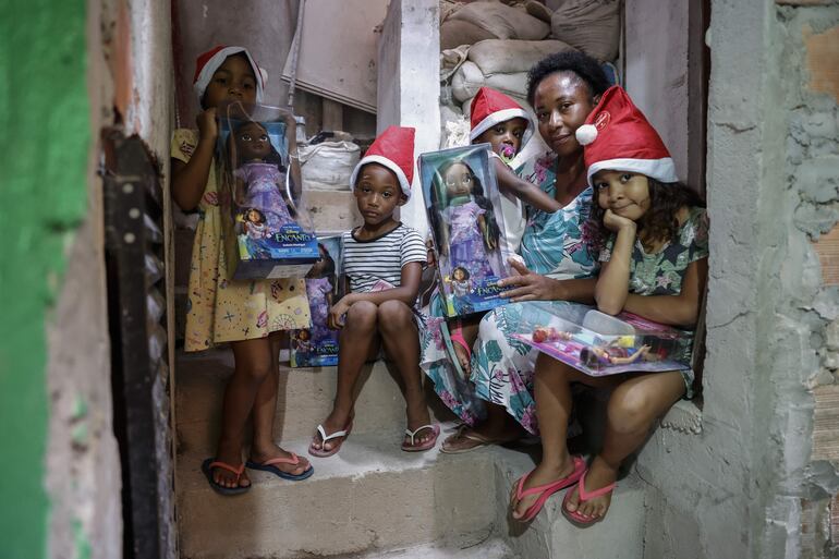 Raimunda da Cruz, madre en situación de desempleo junto a sus dos hijas y sus dos sobrinas posan para fotografía, tras recibir los regalos patrocinado de unos grandes almacenes para celebrar una navidad en Paraisopolis, la segunda mayor favela de São Paulo (Brasil). En las bulliciosas y laberínticas calles de Paraisópolis, los habitantes de la segunda mayor favela de São Paulo se preparan para celebrar una Navidad diferente, marcada por las carencias económicas. 