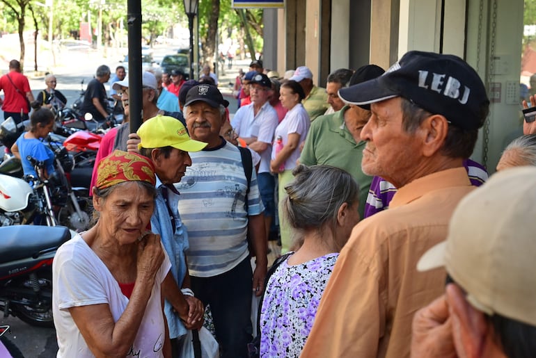 Adultos mayores haciendo fila para cobrar sus beneficios sociales ayer en el microcentro de Asunción.