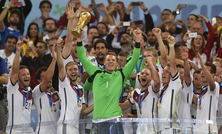 (FILES) Germany's goalkeeper Manuel Neuer (front C) and team-mates celebrate with the World Cup trophy after they won the 2014 FIFA World Cup final football match between Germany and Argentina 1-0 following extra-time at the Maracana Stadium in Rio de Janeiro, Brazil, on July 13, 2014. Germany goalkeeper Manuel Neuer, a 2014 World Cup winner, on August 21, 2024  announced his retirement from international football on social media. Neuer, 38, played 124 matches for Germany, captaining the side 61 times. (Photo by Fabrice COFFRINI / AFP)