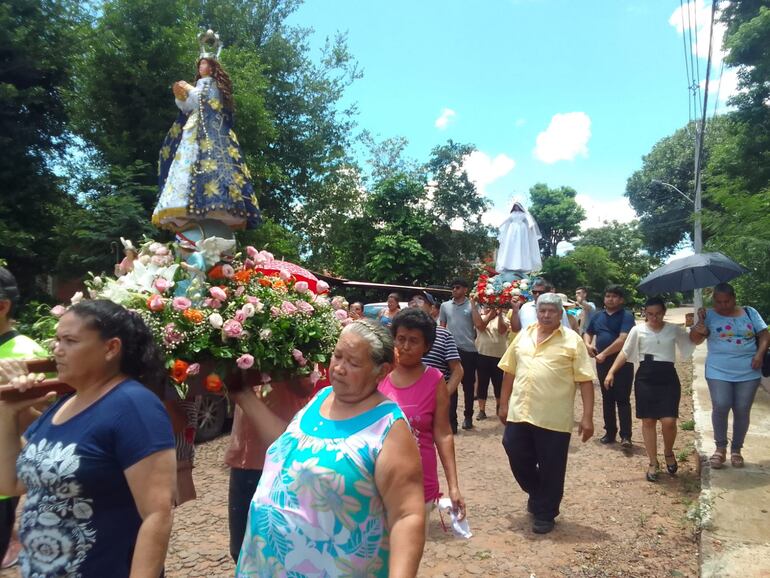 personas llevan a dos imágenes de la Virgen de Caacupé y Medalla Milagrosa, respectivamente.