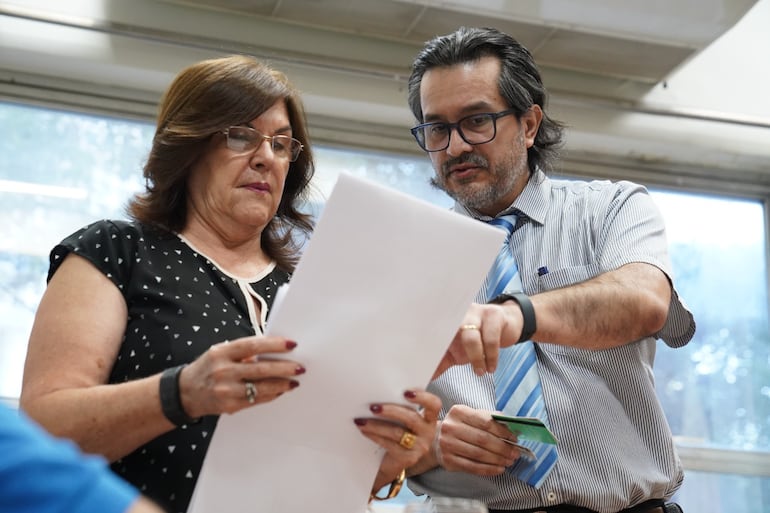 Funcionarios de la Dirección de Jubilaciones observan documentos relacionados a la denuncia presentada por asegurados del IPS.