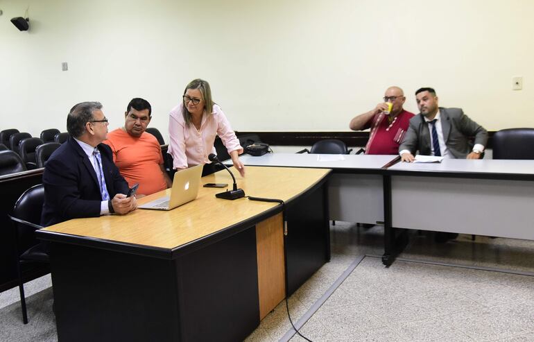 Los policías Osvaldo Vera (remera naranja) y Merardo Palacios (camisa roja) junto a sus abogados, en la sala de juicios.