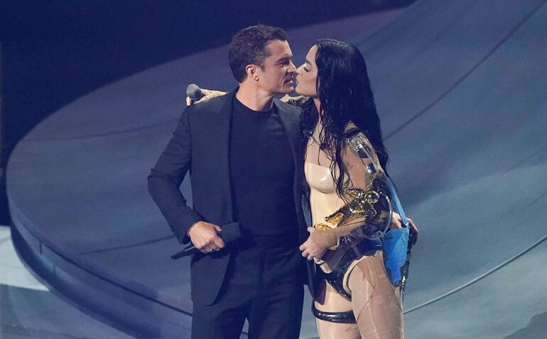 La cantante estadounidense Katy Perry besa a su pareja, el actor inglés Orlando Bloom, mientras sostiene el premio MTV Video Vanguard después de actuar en el escenario durante los MTV Video Music Awards en el UBS Arena en Elmont, Nueva York, el 11 de septiembre de 2024.