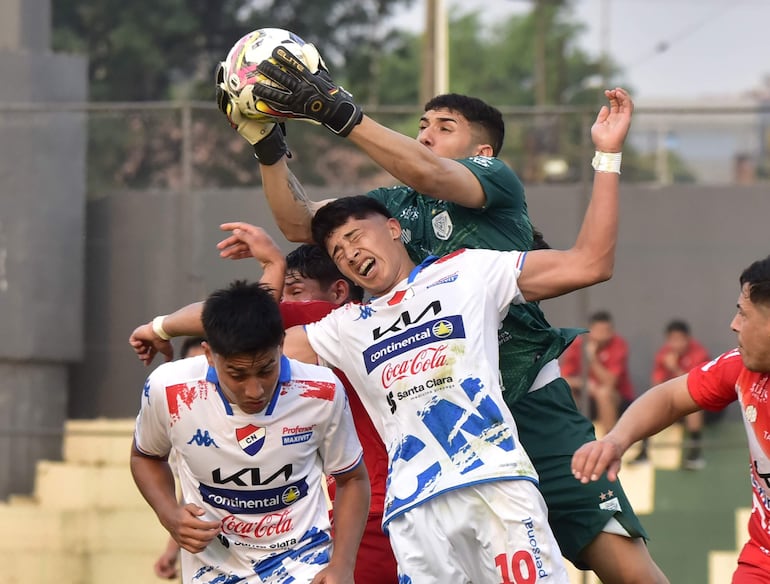 El arquero de Ameliano, Nicolás Rossi, controla el balón ante la arremetida de  los jugadores de Nacional Tiago Caballero (10) y Sebastián Quintana. La Academia no tuvo mucho peso en el juego aéreo.