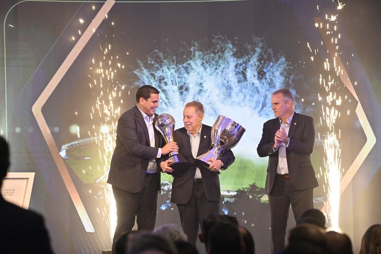 Rubén Di Tore (c), presidente de Libertad, recibe los trofeos de Copa Paraguay y Supercopa Paraguay en compañía de Robert Harrison (i), titular de la Asociación Paraguaya de Fútbol.