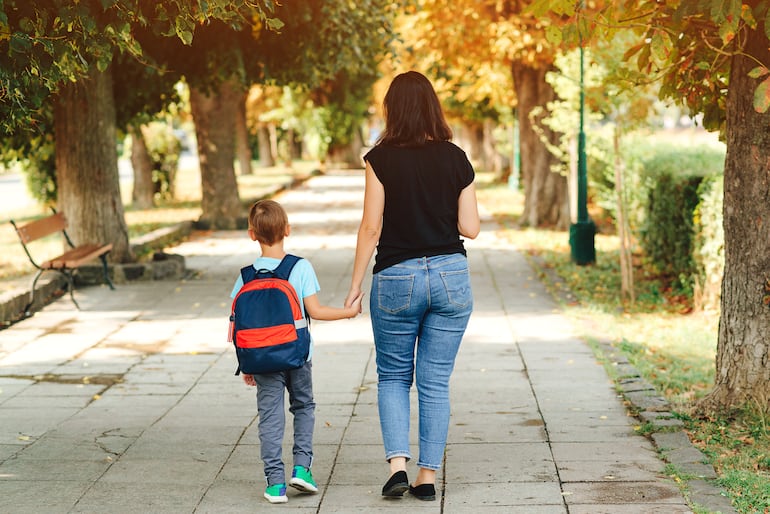 Imagen de referencia. Una madre vestida de forma casual lleva de la mano a su hijo por un camino.