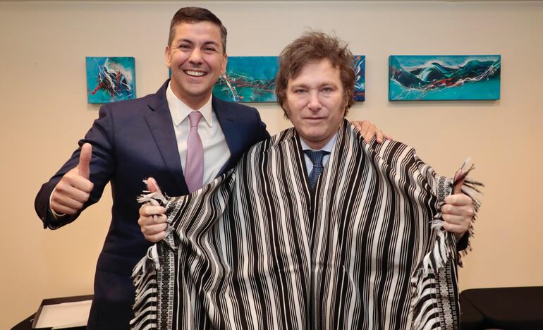 Javier Milei posa con el poncho de para'i de 60 listas junto a Santiago Peña.