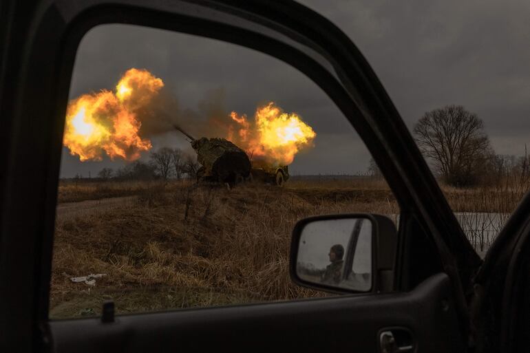 Un soldado ucraniano reflejado en el espejo de un automóvil observa cómo un obús Archer de fabricación sueca operado por miembros ucranianos de la Brigada de Artillería dispara hacia posiciones rusas, en la región de Donetsk, el 20 de enero de 2024, en medio de la invasión rusa de Ucrania.