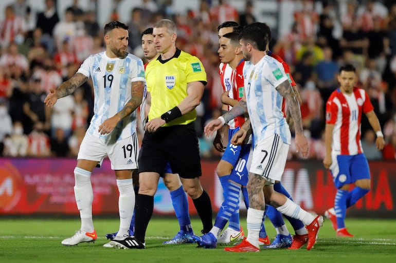 El árbitro brasileño Anderson Daronco es rodeado por jugadores de Paraguay y Argentina en un partido de las Eliminatorias Sudamericanas 2022 en el estadio Defensores del Chaco, en Asunción.